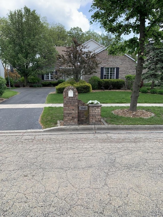 view of property hidden behind natural elements featuring a front lawn