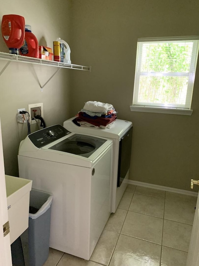 laundry room featuring washing machine and clothes dryer, light tile patterned floors, and baseboards