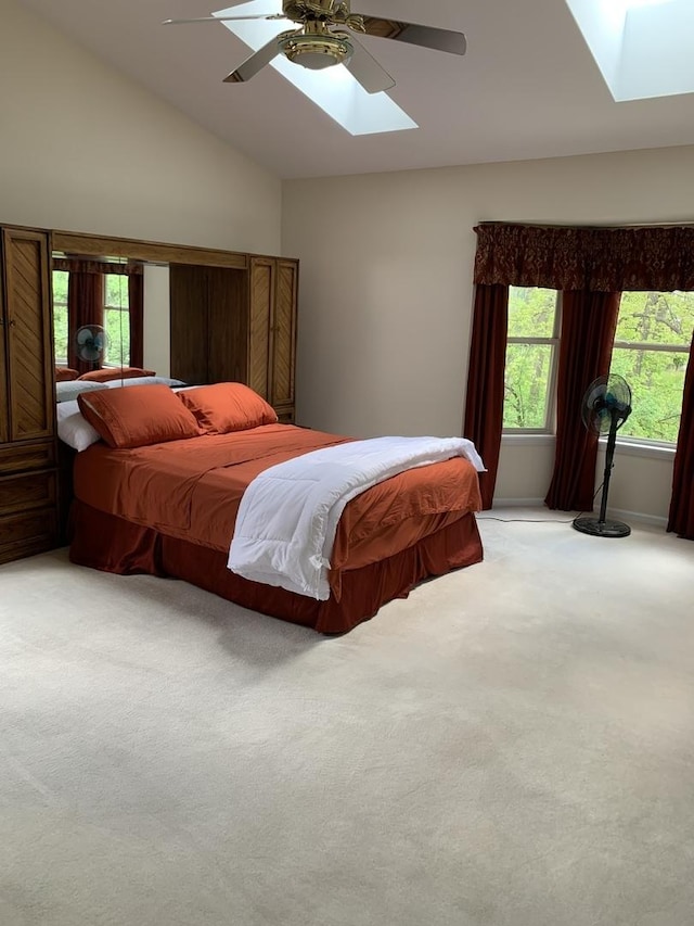 bedroom with a skylight, lofted ceiling, light carpet, and a ceiling fan