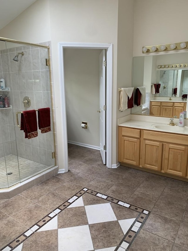 bathroom with a shower stall, vanity, and baseboards