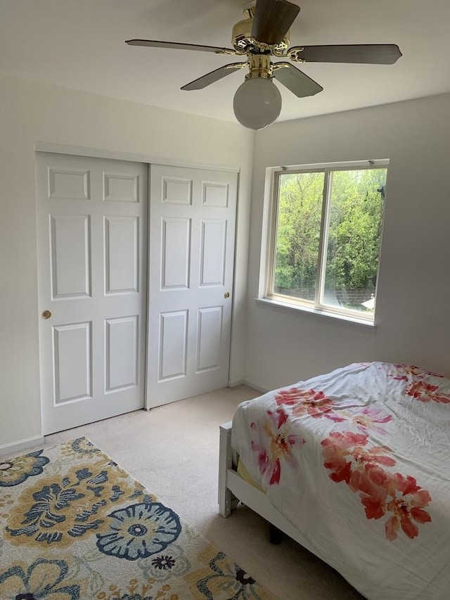 bedroom featuring light colored carpet, a closet, ceiling fan, and baseboards