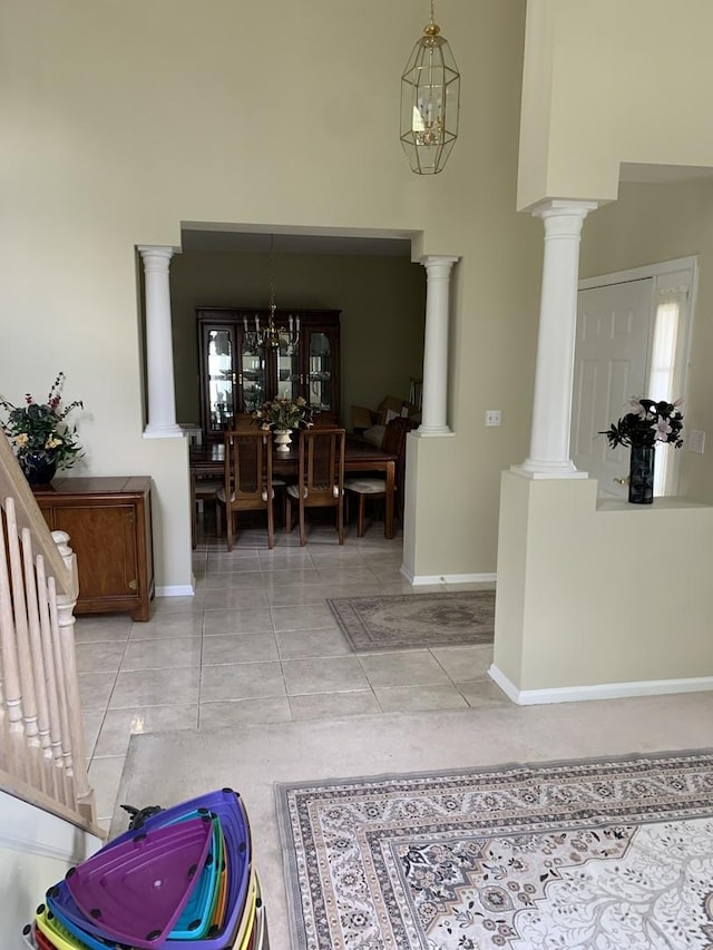 tiled entrance foyer with a high ceiling, baseboards, and decorative columns