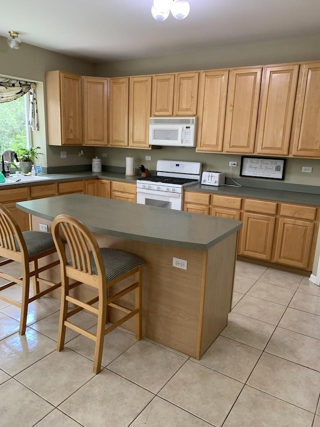 kitchen featuring white appliances, a sink, light brown cabinets, dark countertops, and light tile patterned floors