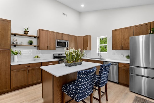 104 S Taylor St, Towanda, IL 61776 - kitchen with stainless steel appliances, a sink, a high ceiling, decorative backsplash, and light wood-style flooring