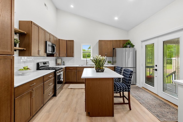 104 S Taylor St, Towanda, IL 61776 - kitchen featuring appliances with stainless steel finishes, open shelves, a kitchen breakfast bar, high vaulted ceiling, and light wood-type flooring