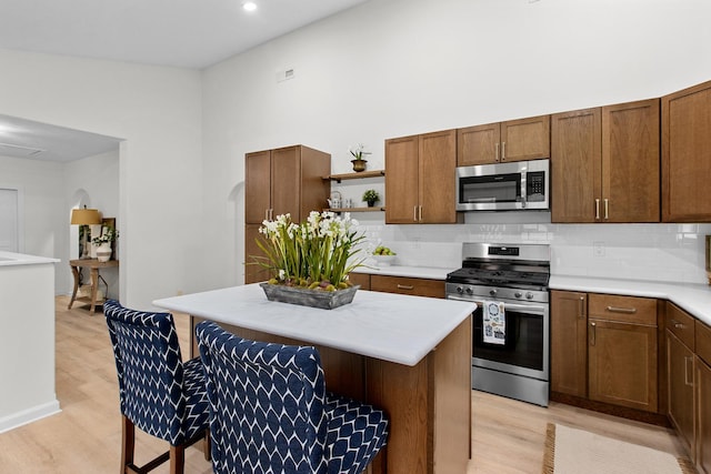 104 S Taylor St, Towanda, IL 61776 - kitchen featuring appliances with stainless steel finishes, open shelves, light wood finished floors, tasteful backsplash, and a towering ceiling
