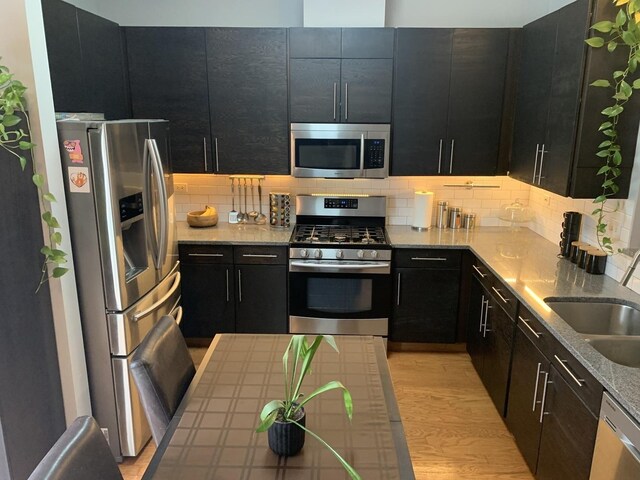 2406 Daybreak Ct, Elgin, IL 60123 - kitchen with appliances with stainless steel finishes, dark cabinets, decorative backsplash, a sink, and light wood-style flooring