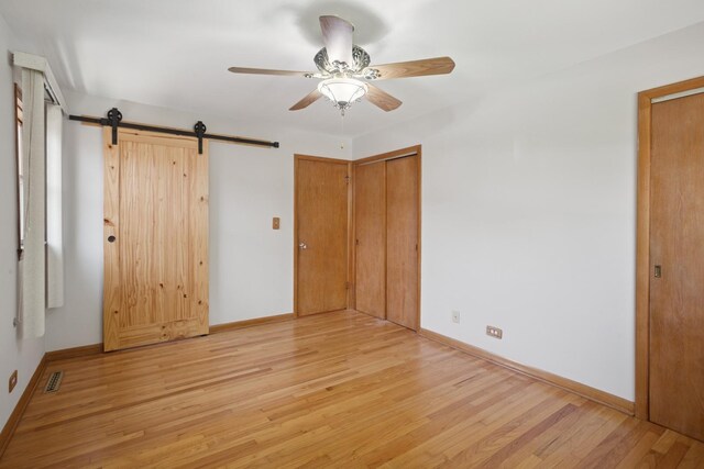 133 Maple Ct, Bloomingdale, IL 60108 - unfurnished bedroom featuring light wood-style floors, multiple closets, baseboards, and a barn door