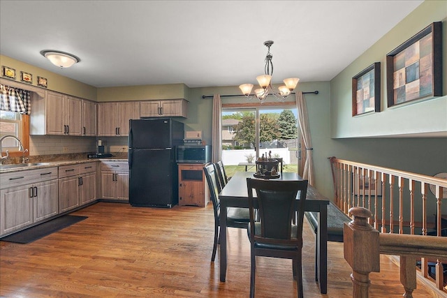 kitchen featuring freestanding refrigerator, stainless steel microwave, a sink, a chandelier, and wood finished floors