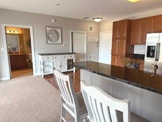 140 S River St Unit 208, Aurora, IL 60506 - kitchen with stainless steel refrigerator with ice dispenser, brown cabinetry, dark countertops, and baseboards