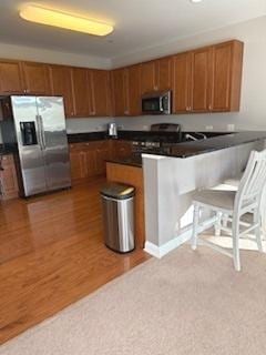 140 S River St Unit 208, Aurora, IL 60506 - kitchen with appliances with stainless steel finishes, brown cabinetry, dark countertops, and a peninsula