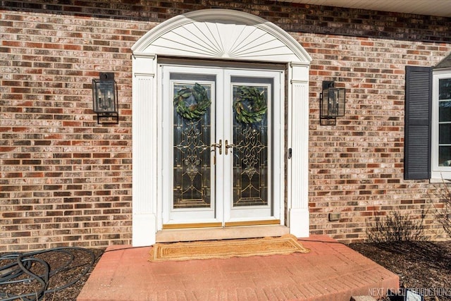 property entrance featuring french doors and brick siding
