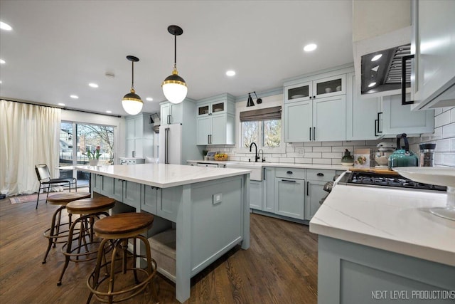 kitchen with tasteful backsplash, dark wood finished floors, a kitchen island, a kitchen bar, and recessed lighting