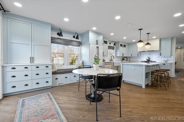 kitchen with light countertops, a kitchen island, tasteful backsplash, a breakfast bar area, and white appliances