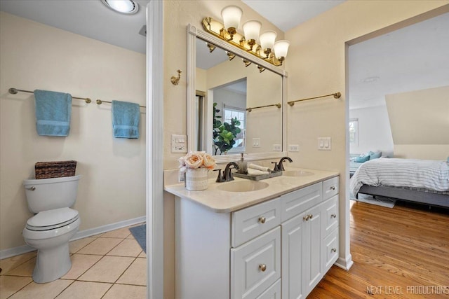 ensuite bathroom featuring toilet, double vanity, and tile patterned flooring