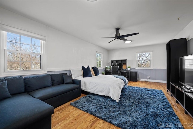 bedroom with wainscoting, wood finished floors, and ceiling fan