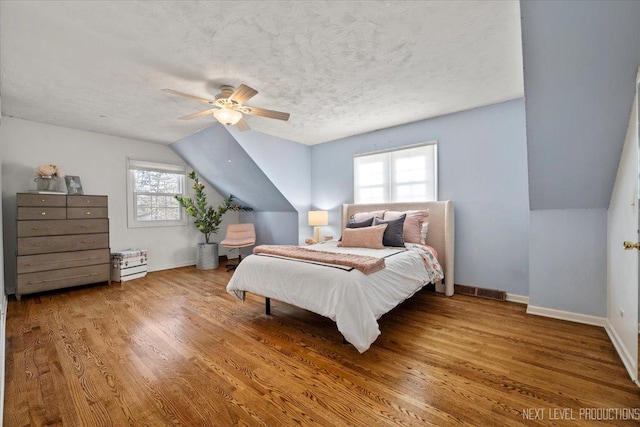 bedroom with lofted ceiling, baseboards, wood finished floors, ceiling fan, and a textured ceiling