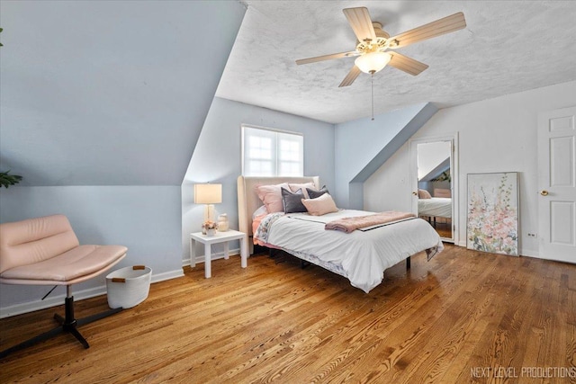 bedroom featuring wood finished floors, baseboards, a textured ceiling, and ceiling fan