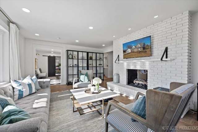 living room featuring a brick fireplace, recessed lighting, and wood finished floors