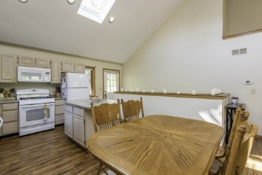 dining area with a skylight, dark wood-type flooring, recessed lighting, and high vaulted ceiling