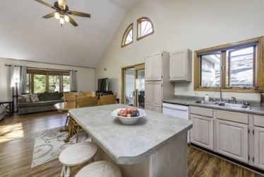 kitchen with high vaulted ceiling, a sink, ceiling fan, white dishwasher, and a kitchen island