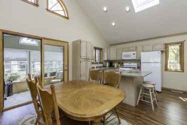 dining room with high vaulted ceiling, dark wood-style floors, and a skylight