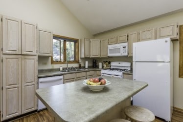 kitchen with white appliances, a sink, dark wood-type flooring, a center island, and a kitchen bar