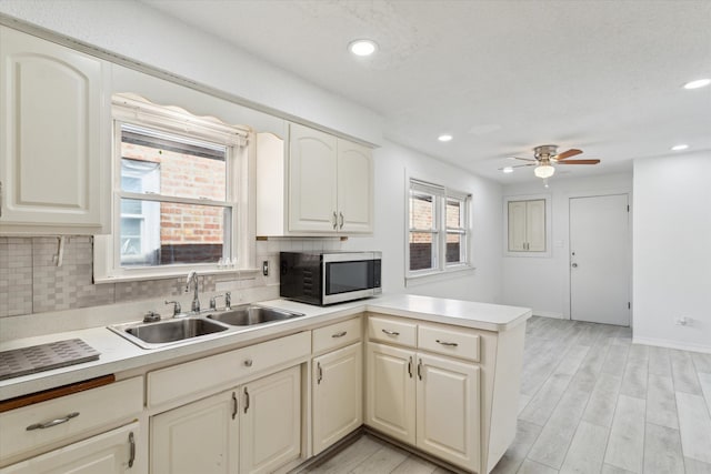 1230 W 112th Pl, Chicago, IL 60643 - kitchen with stainless steel microwave, a sink, a peninsula, tasteful backsplash, and a ceiling fan