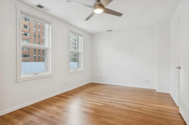 spare room featuring ceiling fan, light wood-style flooring, and baseboards