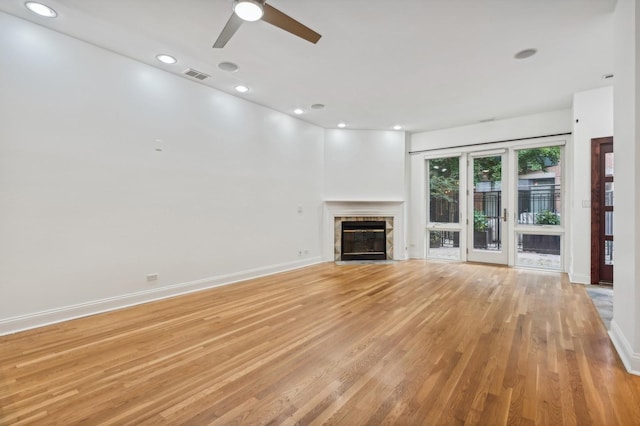 unfurnished living room with light wood-type flooring, a fireplace with flush hearth, ceiling fan, baseboards, and recessed lighting