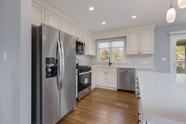 50 Kendal Rd, Elk Grove Village, IL 60007 - kitchen featuring appliances with stainless steel finishes, a sink, light countertops, tasteful backsplash, and hardwood / wood-style floors