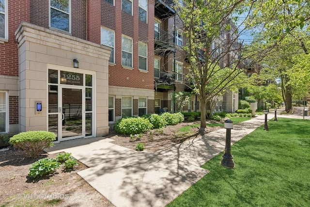entrance to property with brick siding and a lawn