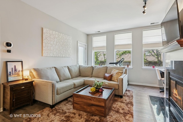 living room with wood finished floors, rail lighting, a high end fireplace, and baseboards