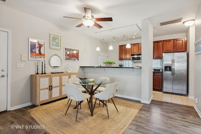 dining space with track lighting, a ceiling fan, light wood-style floors, and baseboards