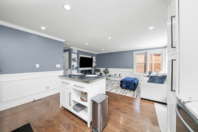 kitchen with ornamental molding, wainscoting, white cabinets, open floor plan, and dark wood-style flooring