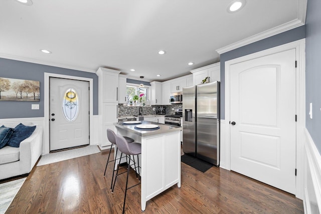 kitchen featuring appliances with stainless steel finishes, ornamental molding, recessed lighting, a kitchen breakfast bar, and white cabinets
