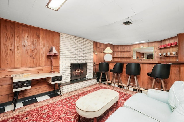 living area featuring wood walls, a dry bar, and a brick fireplace