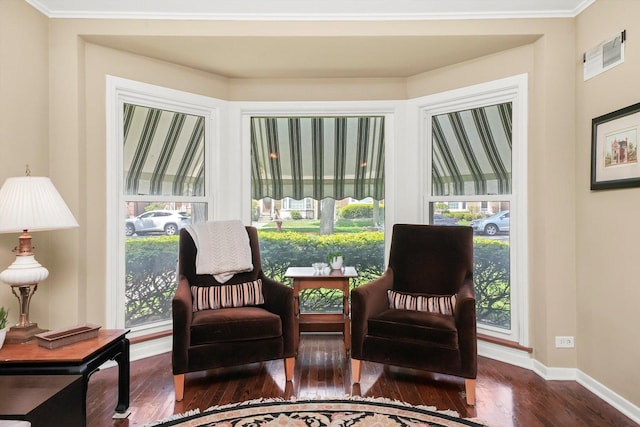 living area featuring wood finished floors, healthy amount of natural light, baseboards, and ornamental molding