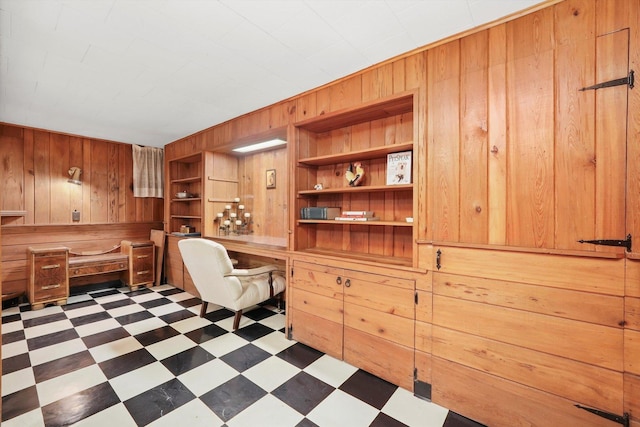 office area with wooden walls, built in study area, and dark flooring