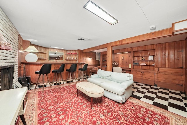 living area featuring wood walls, a dry bar, tile patterned floors, and a fireplace
