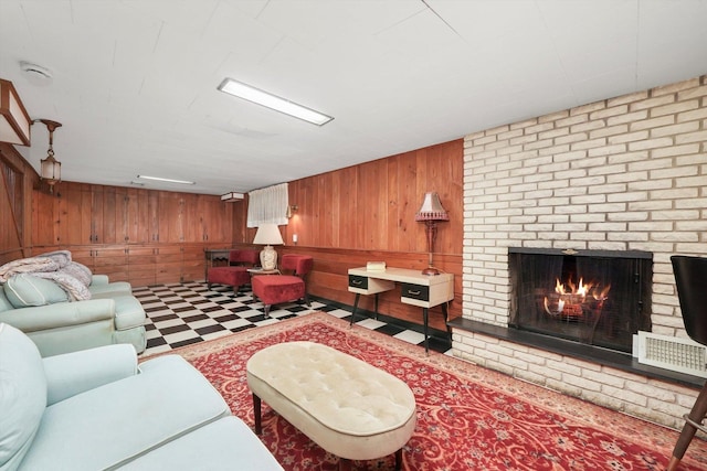 living area featuring wood walls, tile patterned floors, and a brick fireplace