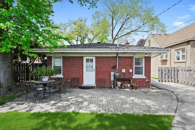 rear view of house with brick siding, fence, and a patio