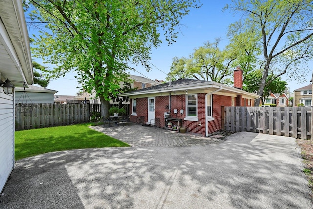 view of front of house with brick siding, a chimney, and a patio