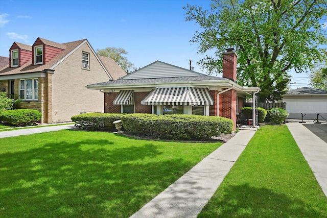 view of front of home with brick siding, a front yard, and a chimney