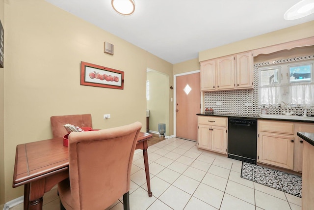 kitchen featuring black dishwasher, dark countertops, tasteful backsplash, a sink, and light tile patterned floors