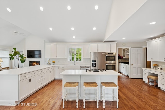11 Longmeadow Rd, Winnetka, IL 60093 - kitchen featuring appliances with stainless steel finishes, lofted ceiling, a peninsula, a kitchen bar, and white cabinets