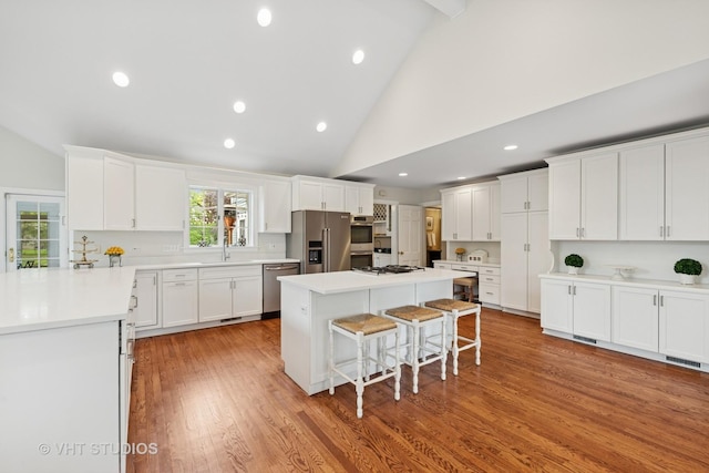 11 Longmeadow Rd, Winnetka, IL 60093 - kitchen with appliances with stainless steel finishes, a kitchen breakfast bar, white cabinetry, a kitchen island, and recessed lighting