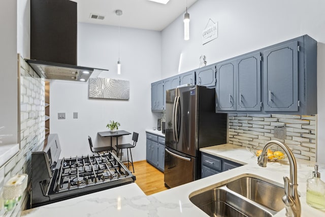 kitchen featuring extractor fan, a sink, freestanding refrigerator, backsplash, and gas stove