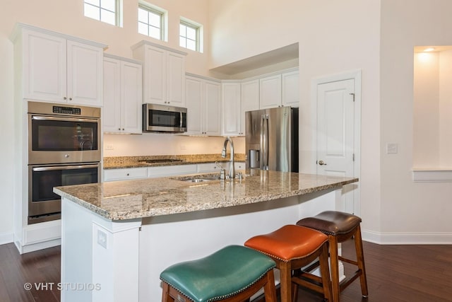 3815 Ridge Pointe Dr, Geneva, IL 60134 - kitchen with appliances with stainless steel finishes, a high ceiling, dark wood-style floors, light stone counters, and white cabinets