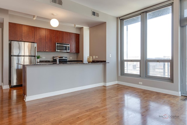 565 W Quincy St Unit 1206, Chicago, IL 60661 - kitchen featuring stainless steel appliances, light wood-type flooring, a peninsula, dark stone countertops, and baseboards